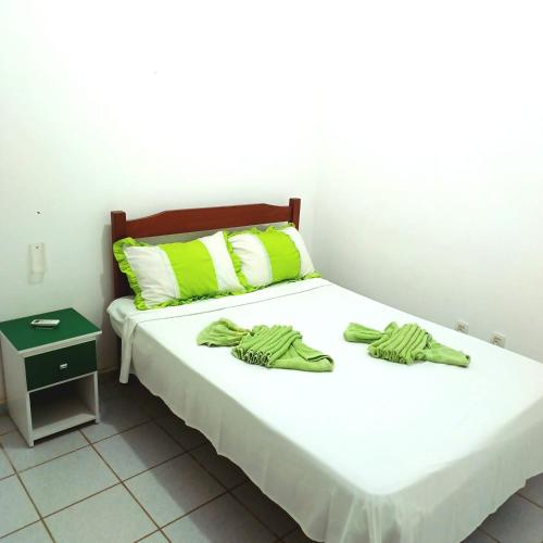 a bedroom with a bed with green towels on it at Condominio Oliveira in Maragogi