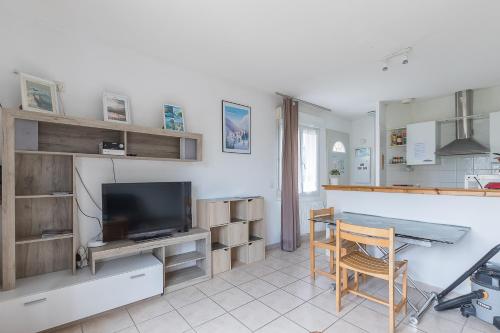 un salon avec une table et une télévision dans l'établissement Le Cairn du Morgon - Appt vue montagne 4p, à Savines