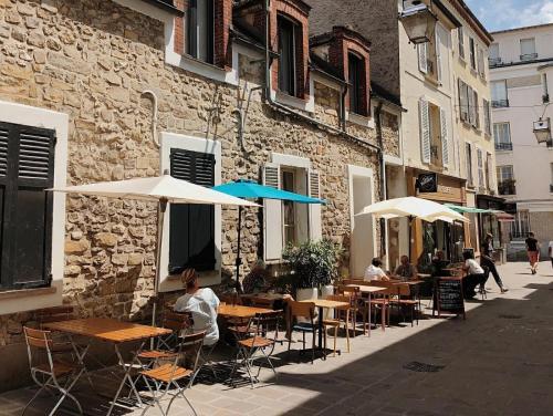 un café en plein air avec des tables et des parasols dans une rue dans l'établissement Studio Moderne à 5 min à pied du Château, à Fontainebleau