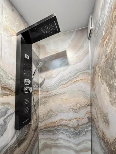 La salle de bains est pourvue d'une douche et d'un mur en pierre. dans l'établissement Studio Moderne à 5 min à pied du Château, à Fontainebleau