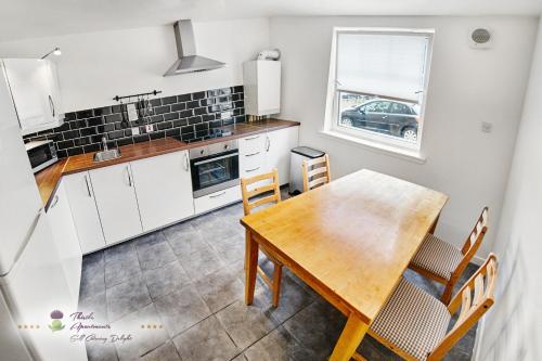 a kitchen and dining room with a wooden table and chairs at Thistle Apartments - King's Apartment in Aberdeen