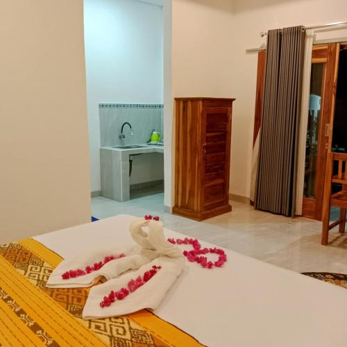 a bed with white towels and pink flowers on it at Villa Jepun Lovina in Lovina