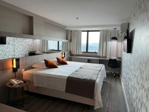 a bedroom with a large bed and a desk at Logic Hotel Volta Redonda in Volta Redonda