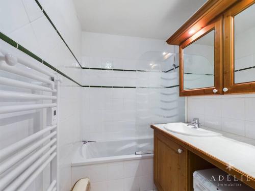 une salle de bain blanche avec un lavabo et une baignoire dans l'établissement Appartement 3* avec terrasse exposée sud, proche des pistes et commerces, parking inclus - FR-1-398-535, à Montvalezan