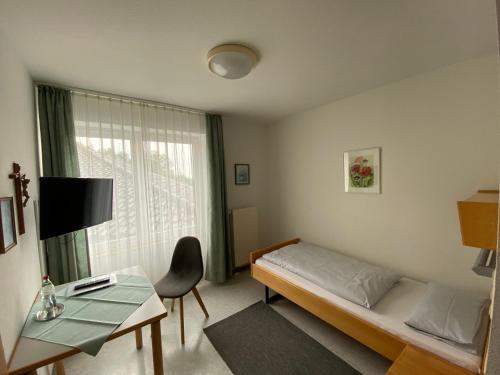 a room with a bed and a table and a window at Schönstattzentrum Aulendorf in Aulendorf