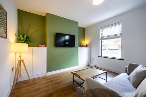a living room with a couch and a tv on a wall at Beautiful 2 Bedroom House in Atherton, Free Parking in Atherton