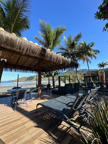a patio with a table and chairs and a straw umbrella at Brisa do Mar Barê Praia Hotel - Praia de BAREQUEÇABA in São Sebastião