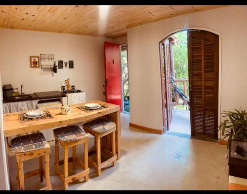 uma cozinha com uma mesa e cadeiras de madeira e uma porta aberta em Aconchego Penedo em Penedo