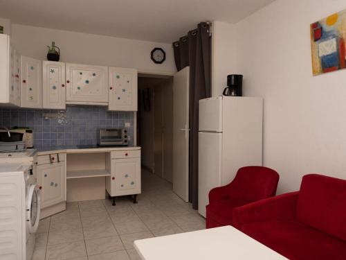 Il comprend une cuisine équipée d'un réfrigérateur blanc et d'une chaise rouge. dans l'établissement Studio cabine avec jardin privé face plage du Lavandou - 4 couchages - FR-1-803-52, au Lavandou