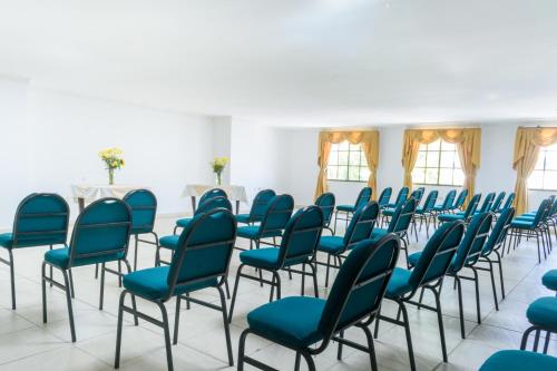 a room with blue chairs and tables and windows at Hotel Caribe Plaza Barranquilla in Barranquilla