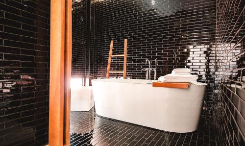 a bathroom with a white tub and black tiles at Sichon Cabana Beach Resort in Sichon