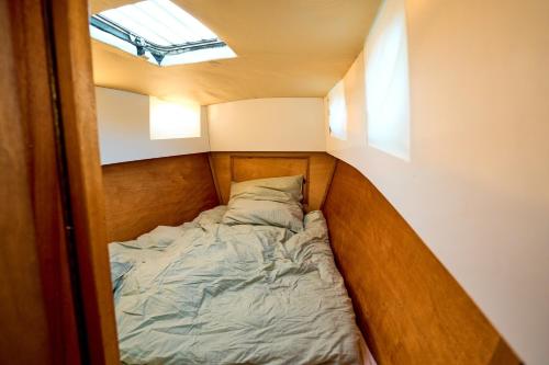 een klein bed in een kleine kamer met een raam bij Gemütliches Wohnschiff in Brandenburg an der Havel