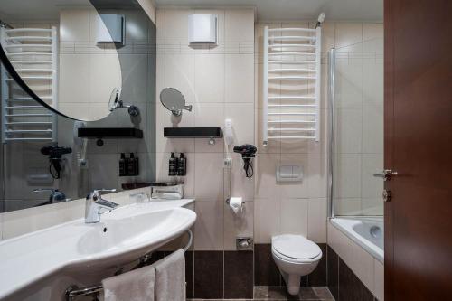 a bathroom with a sink and a toilet and a mirror at Eurostars Queen of Montenegro in Budva