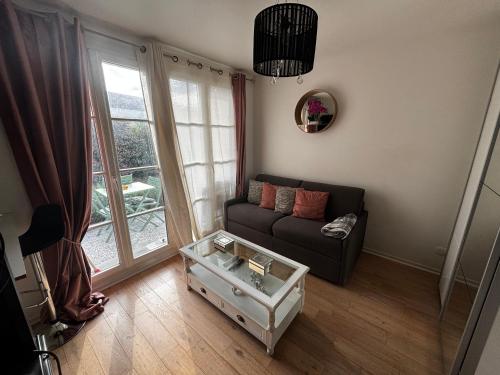 a living room with a couch and a glass coffee table at Cosy Disney Studio - Disneyland Paris in Chanteloup-en-Brie