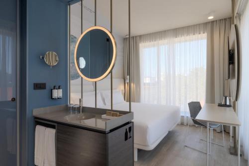 a bathroom with a tub and a sink and a mirror at Occidental Ljubljana in Ljubljana