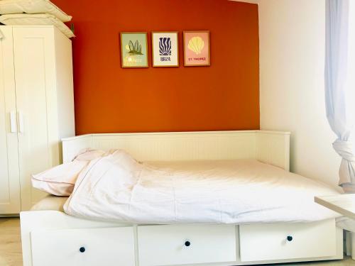 Ce lit se trouve dans une chambre dotée d'un mur orange. dans l'établissement Le Clos des Flots Proche plages et centre ville, à Carqueiranne