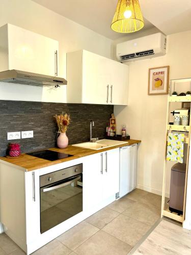 une cuisine avec des armoires blanches et un évier dans l'établissement Le Clos des Flots Proche plages et centre ville, à Carqueiranne