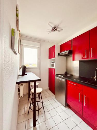- une cuisine avec des placards rouges et une table dans l'établissement Studio Saint-Remi I Pommery, à Reims