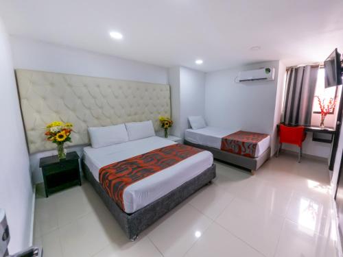 a hotel room with two beds and a red chair at Hotel Caribe Plaza Barranquilla in Barranquilla