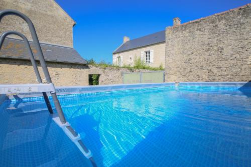 - une piscine avec une échelle en face d'un bâtiment dans l'établissement LA FERME DE LONGUES maisons spécialisées pour les familles avec jeunes enfants, à Longues-sur-Mer