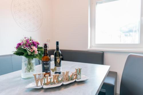 a table with two bottles of wine and a vase of flowers at Ferienhaus Treissmann an der Weinstraße in Leutschach
