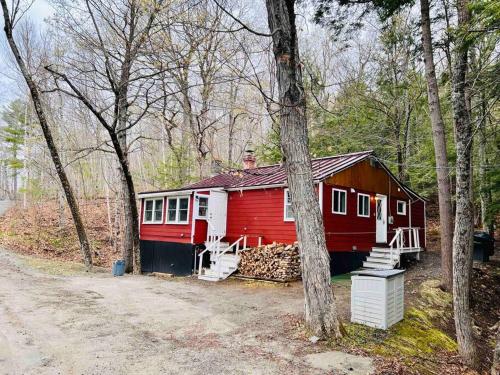 ein rot-weißes Haus im Wald in der Unterkunft Lakefront Cottage on Brewer Lake in Holden