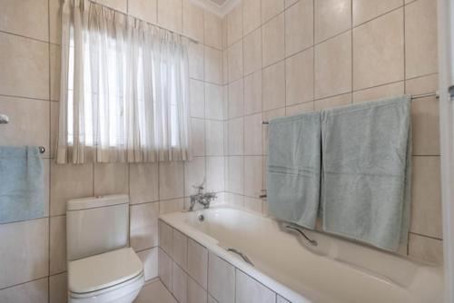 Un baño con bañera, inodoro y ventana. en 19 Hill Street, en Plettenberg Bay