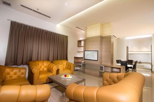sala de estar con muebles de color amarillo y TV en Whiz Prime Hotel Kelapa Gading en Yakarta