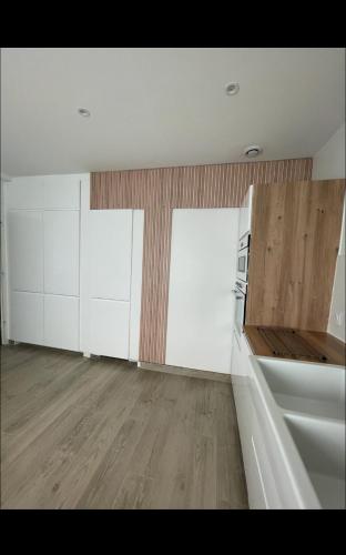 une cuisine vide avec des placards blancs et du parquet dans l'établissement Villa T5 avec Jacuzzi proche centre ville Darcy, à Dijon
