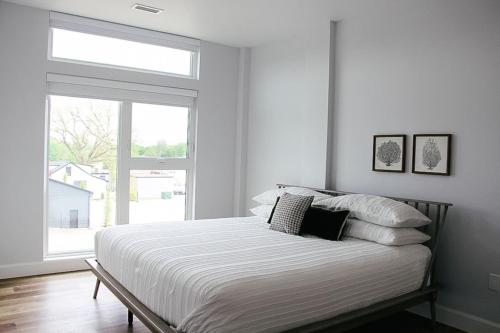 a bed in a white room with a window at Beachview getaway at the New Carlyle 202 on the Main strip in Grand Bend in Grand Bend
