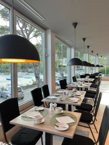a row of tables and chairs in a room with windows at Hotel Cavtat in Cavtat