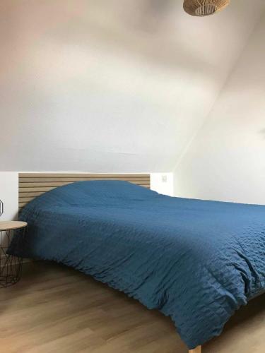 - un lit avec une couette bleue dans une chambre dans l'établissement Duplex à la mer, à Binic