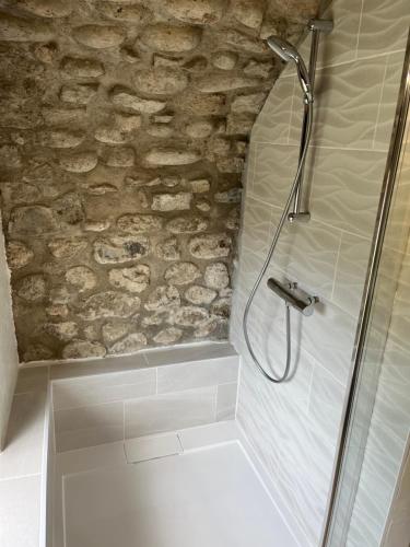 a shower in a bathroom with a stone wall at GITE DE LA CAPPELLA - CHAMBRE D'HÔTES A VOLTA in Aubenas