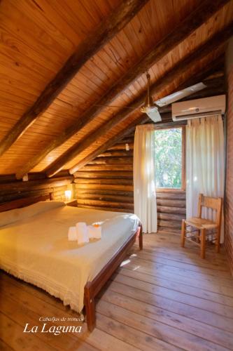 a bedroom with a bed in a log cabin at La Laguna - Cabañas de Troncos in Merlo