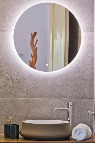 un bagno con specchio rotondo sopra un lavandino di Myrthea Luxury Villas a Karpathos