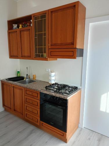 a kitchen with wooden cabinets and a stove top oven at Domus Anna in Montegrotto Terme