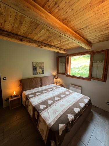une chambre avec un grand lit avec un plafond en bois dans l'établissement La Maison de Sofia, à Montgenèvre
