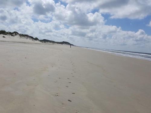 a beach with footprints in the sand and the ocean at Olde Toornblick in Borkum