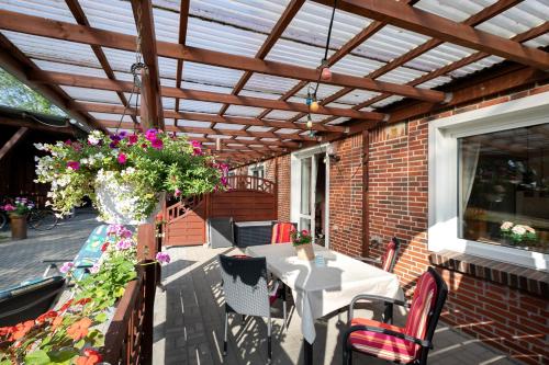 a patio with a wooden pergola and a table with flowers at Bi Tiessens to Hus in Arkebek