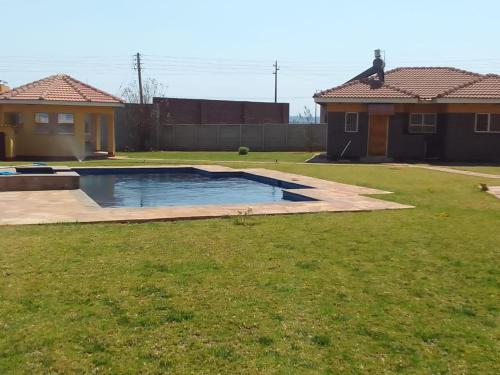 a swimming pool in a yard next to a house at Pomona BB House in Harare