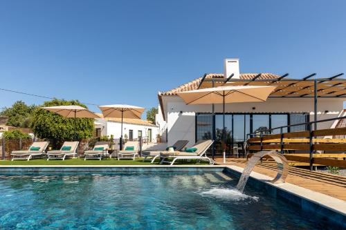 a house with a swimming pool with umbrellas at Alfarrobeiras NATURE -Agroturismo in Olhão