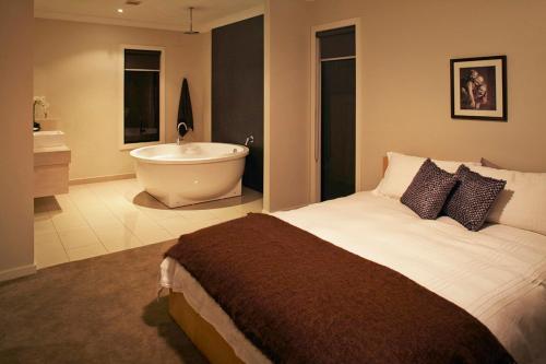 a bedroom with a large bed and a bath tub at Stylish Living- Fireplace, WiFi, Linen, 4 bdrm, Beach 850m in Inverloch