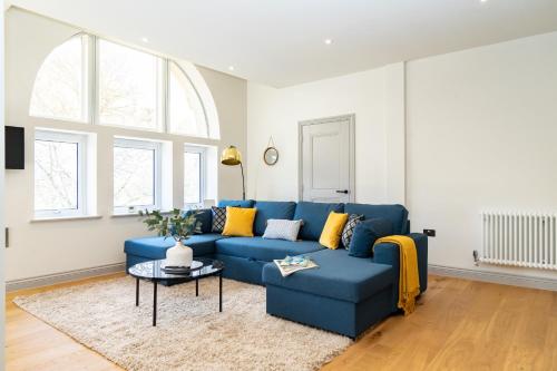 a blue couch in a living room with a table at The Old Glassworks by Bevolve in Shrewsbury