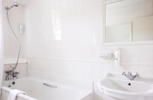 a white bathroom with a tub and a sink at The Coleshill by Greene King Inns in Coleshill