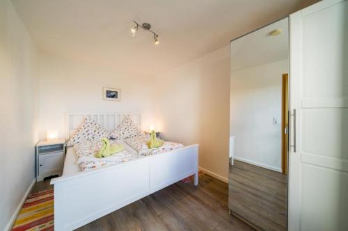 a bedroom with a white bed with green pillows at Ferienwohnug Strandflieder in Borkum