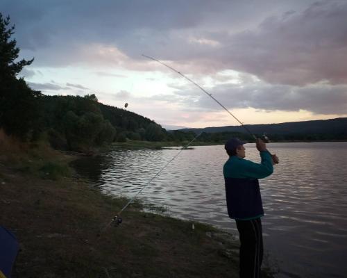a man holding a fishing rod on a lake at Zodiac House in Samokov