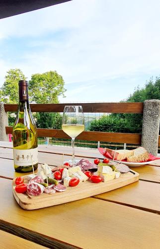 une bouteille de vin et une planche à découper avec de la viande et du fromage dans l'établissement Chambres d'hôtes Les Violles, à Chirac