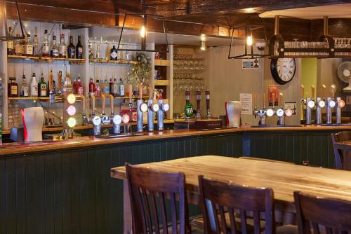 a bar with a wooden table in a restaurant at The Coleshill by Greene King Inns in Coleshill