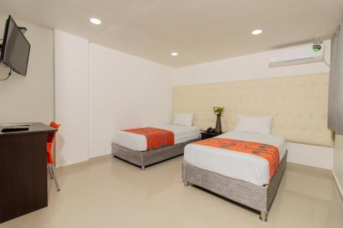 two beds in a room with a tv and a television at Hotel Caribe Plaza Barranquilla in Barranquilla