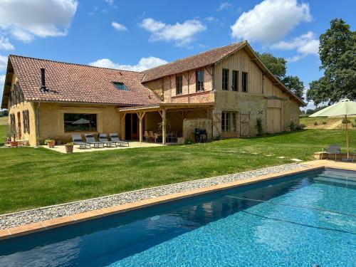 une maison avec une piscine devant une maison dans l'établissement Maison Puchouaou gite 12 personnes, à Montesquiou